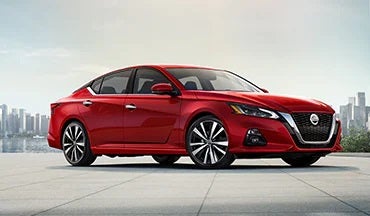 2023 Nissan Altima in red with city in background illustrating last year's 2022 model in Alpine Nissan in Denver CO